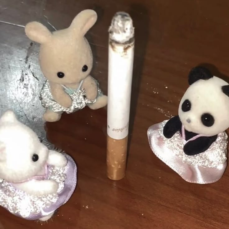 bunny, cat, and panda toys sitting in a circle with a giant lit cigarette in the middle